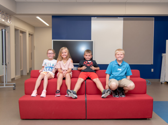 kids smiling at school on a couch - adams central elementary school hastings nebraska
