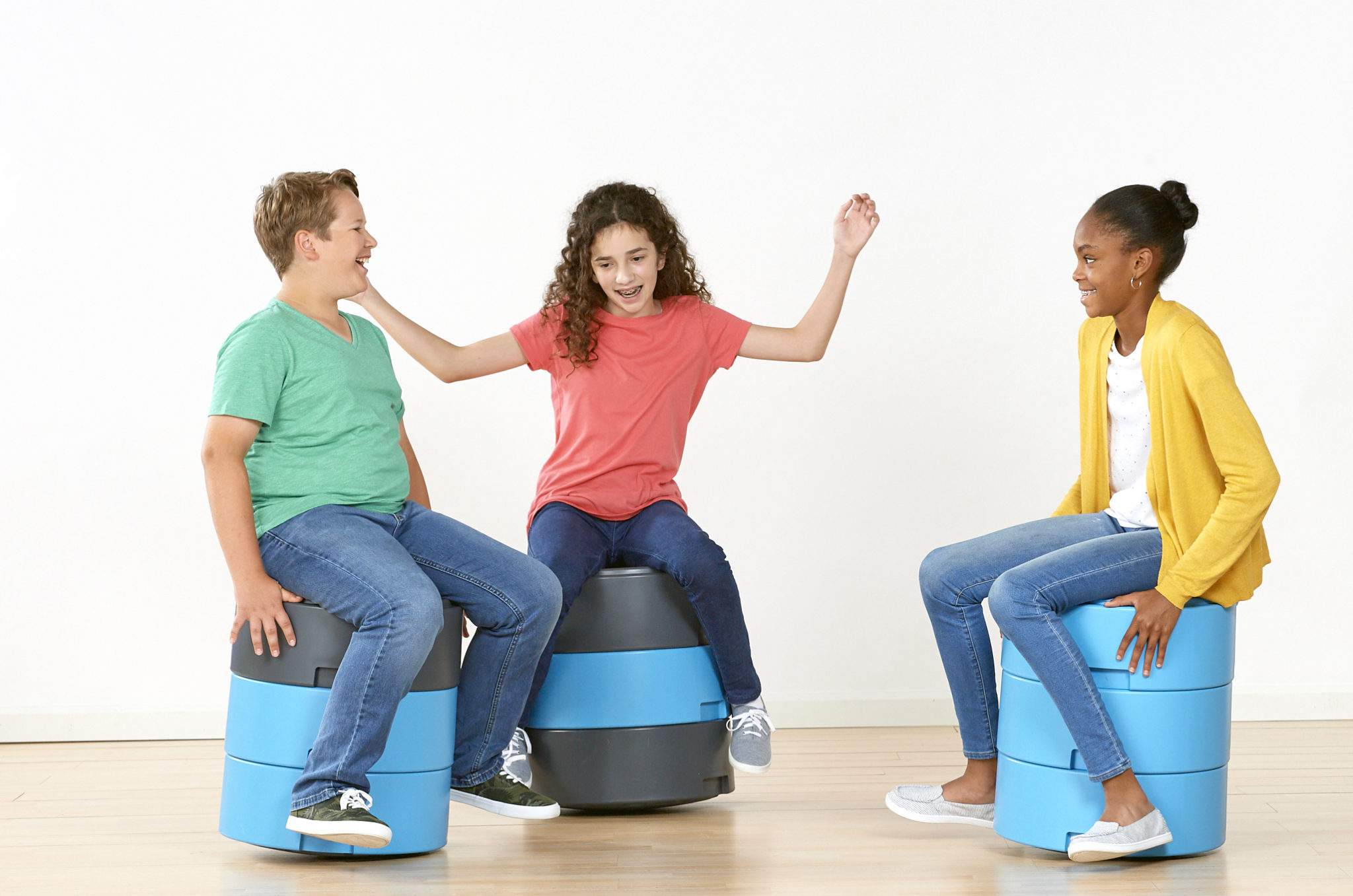 A photograph of 3 children having fun on classroom stools